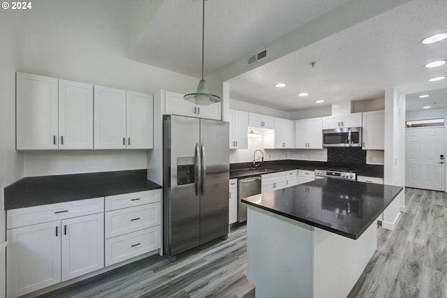 kitchen featuring white cabinets, stainless steel appliances, sink, and a kitchen island