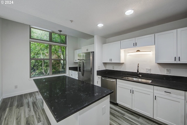 kitchen with a kitchen island, dark wood-type flooring, sink, white cabinets, and appliances with stainless steel finishes