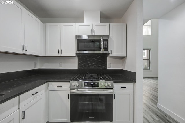 kitchen featuring wood finished floors, baseboards, white cabinetry, and stainless steel appliances