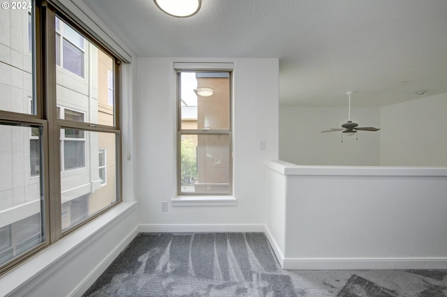 carpeted empty room with baseboards and a ceiling fan