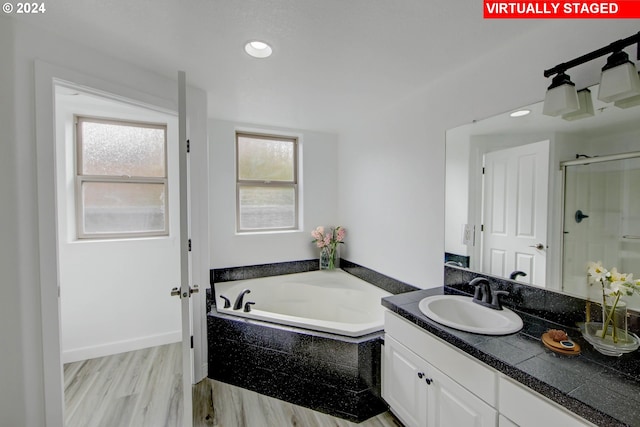 full bathroom featuring a stall shower, a healthy amount of sunlight, vanity, and a garden tub
