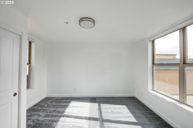 empty room featuring dark carpet and baseboards