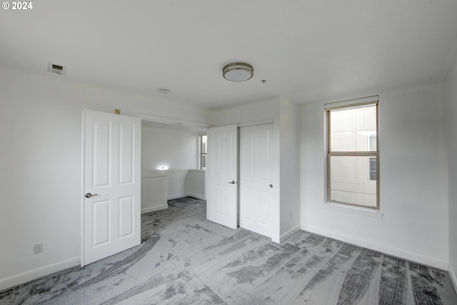 unfurnished bedroom featuring light carpet and a closet