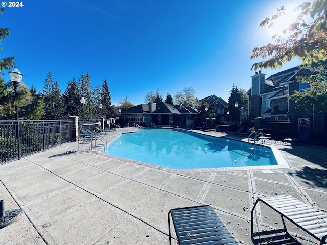 community pool with a patio, a residential view, and fence