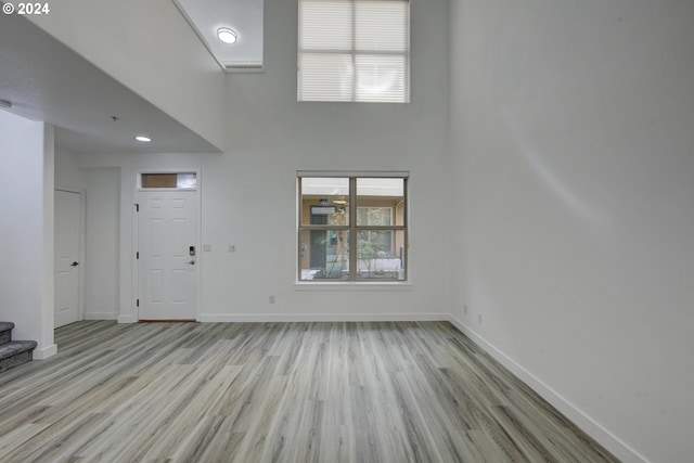 unfurnished living room featuring a high ceiling, wood finished floors, and baseboards