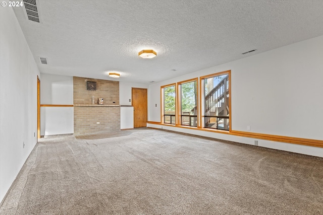 spare room featuring carpet, a textured ceiling, and a fireplace