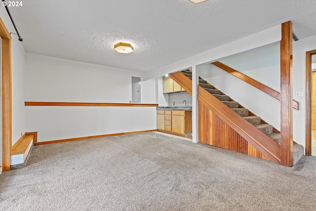 unfurnished living room featuring carpet, sink, and a textured ceiling