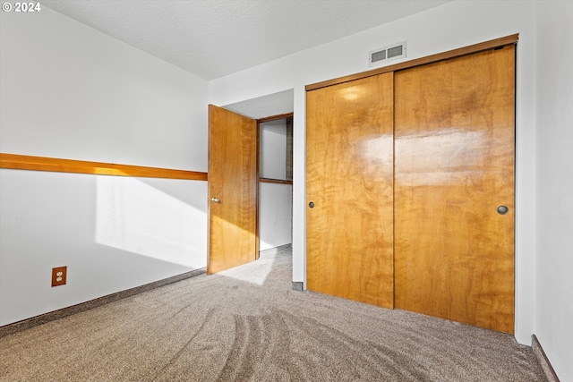 unfurnished bedroom featuring a closet, light colored carpet, and a textured ceiling