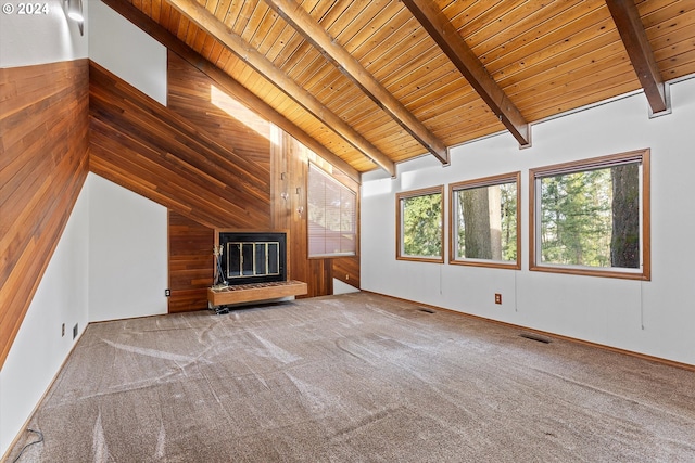 unfurnished living room with beam ceiling, wood walls, and light carpet