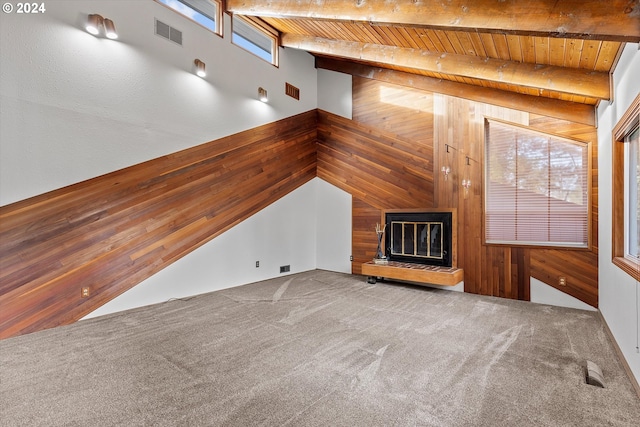 unfurnished living room featuring carpet flooring, plenty of natural light, wooden ceiling, and wood walls