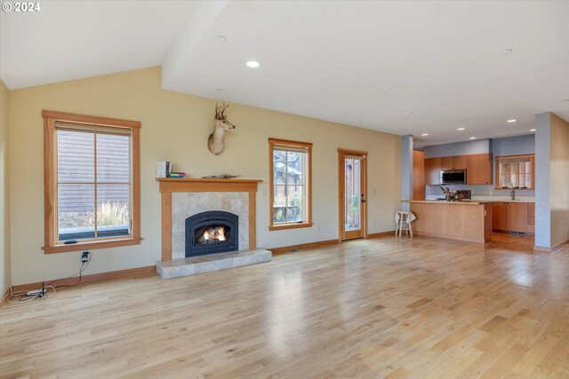 unfurnished living room with light hardwood / wood-style floors, lofted ceiling, and a healthy amount of sunlight