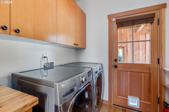 clothes washing area with independent washer and dryer, cabinets, and light wood-type flooring