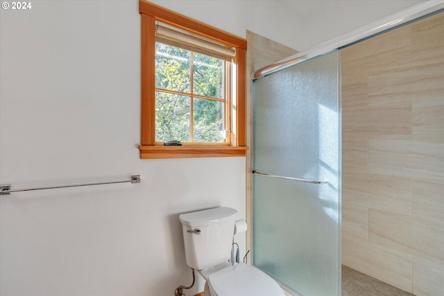 bathroom with a shower with shower door and toilet