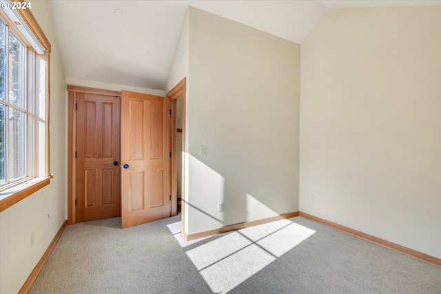 unfurnished bedroom with vaulted ceiling and light colored carpet