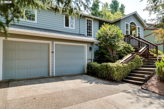 view of front of home featuring a garage, concrete driveway, roof with shingles, and stairs