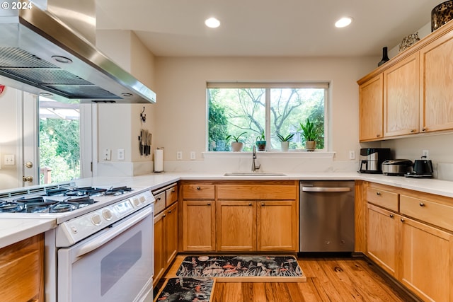 kitchen featuring white gas range, recessed lighting, stainless steel dishwasher, a sink, and wall chimney range hood