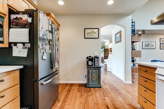 kitchen with arched walkways, light wood-style flooring, recessed lighting, stainless steel appliances, and light countertops