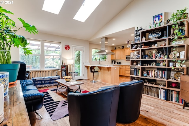 living area featuring lofted ceiling with skylight and light wood-style floors