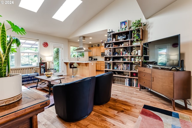 living room with high vaulted ceiling, a skylight, and light wood-style flooring