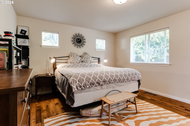 bedroom featuring dark wood finished floors, visible vents, and baseboards