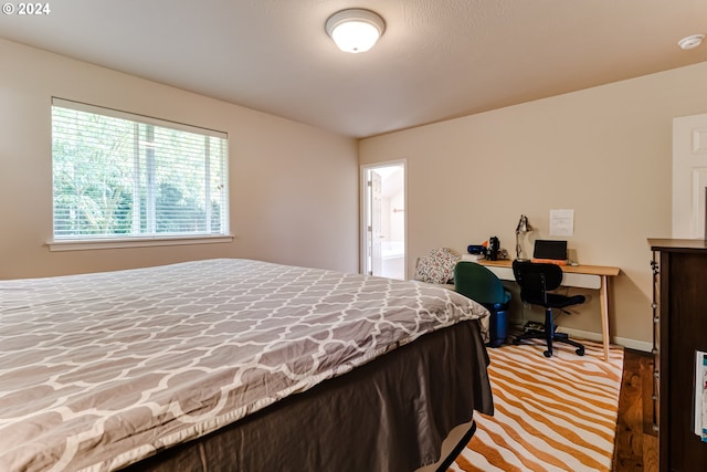 bedroom featuring ensuite bath and baseboards