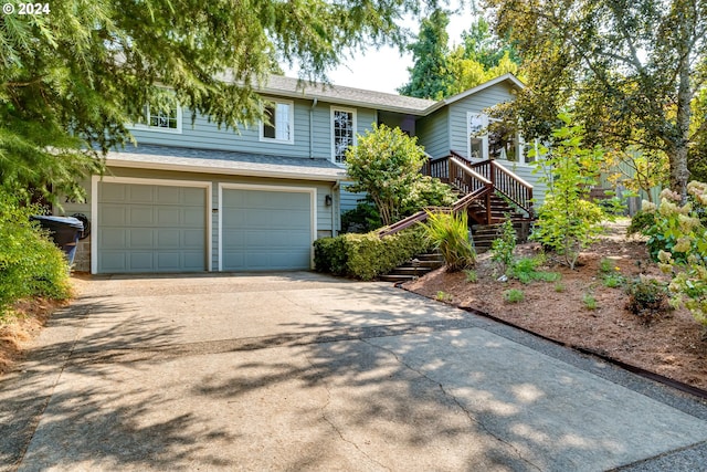 view of front of house with driveway, an attached garage, stairway, and roof with shingles