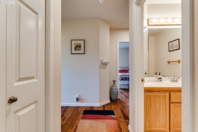 bathroom with baseboards, wood finished floors, and vanity