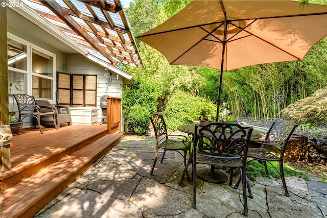 view of patio featuring a wooden deck, a pergola, and outdoor dining space