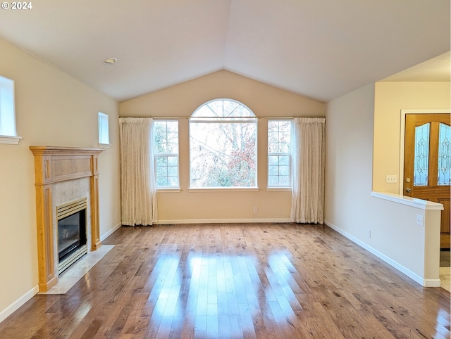 unfurnished living room featuring vaulted ceiling, a fireplace, wood finished floors, and baseboards