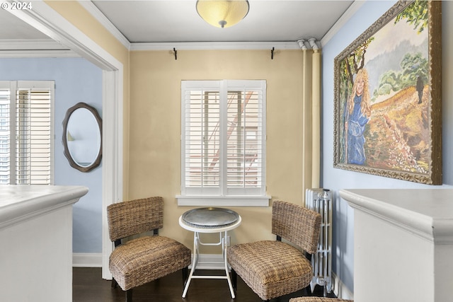 sitting room with plenty of natural light, dark wood-type flooring, radiator, and ornamental molding