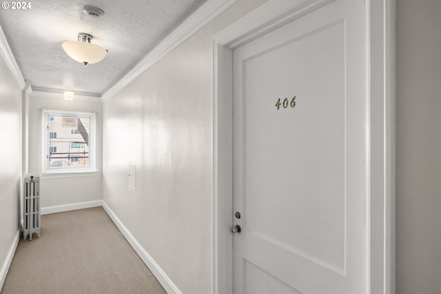 hall with a textured ceiling, carpet floors, radiator, and ornamental molding