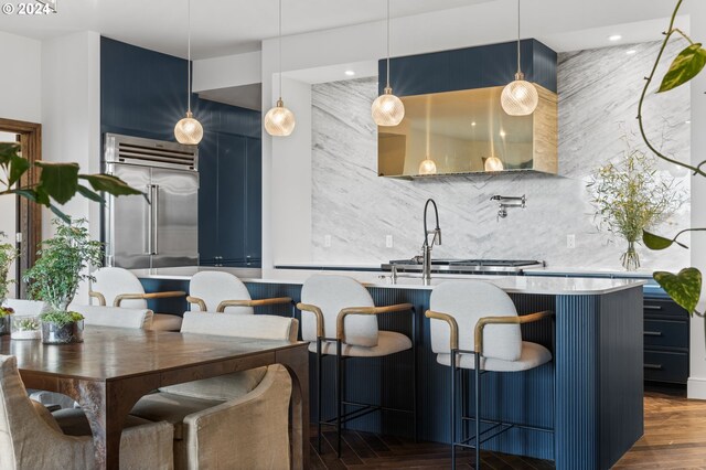 kitchen featuring a kitchen breakfast bar, tasteful backsplash, pendant lighting, blue cabinetry, and dark hardwood / wood-style floors