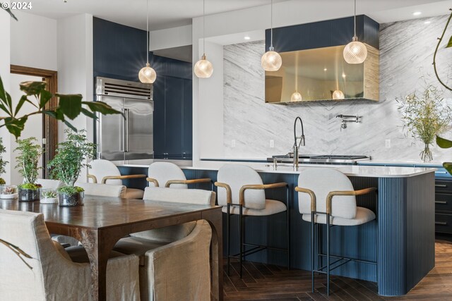 interior space featuring blue cabinets, decorative light fixtures, dark wood-type flooring, and decorative backsplash