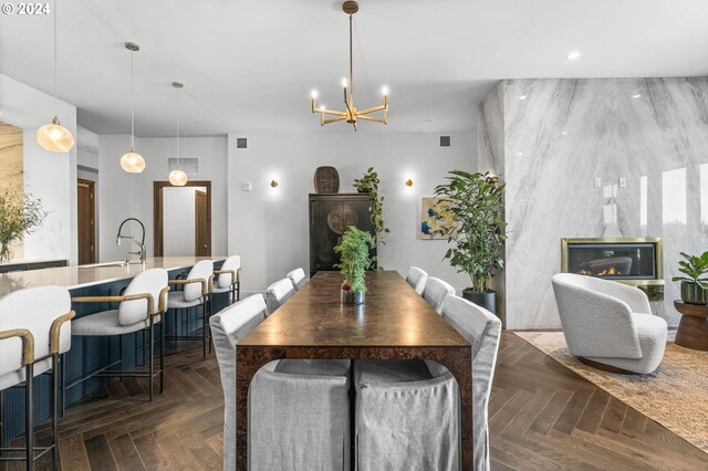 dining room with sink, a chandelier, and dark parquet flooring