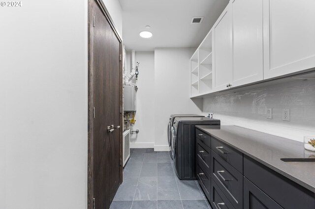 washroom with water heater, washing machine and dryer, and cabinets