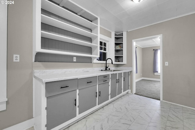 kitchen with light colored carpet, ornamental molding, and sink