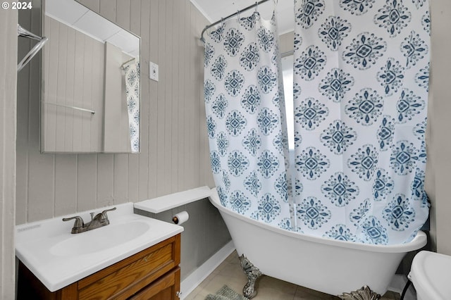 bathroom with toilet, tile patterned floors, wooden walls, a bathing tub, and vanity