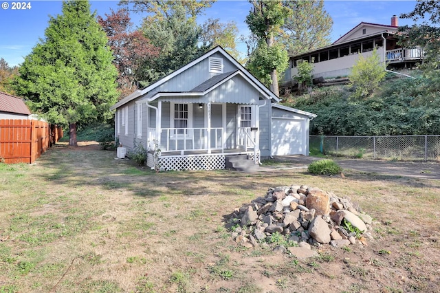 view of front of property featuring a front lawn, covered porch, and a garage