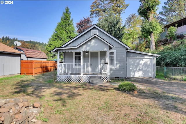 bungalow-style house with covered porch, a garage, and a front lawn