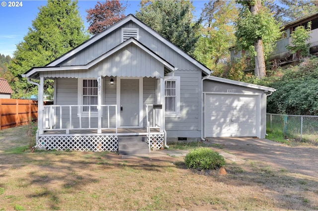 view of front of home with a porch, a front yard, and a garage