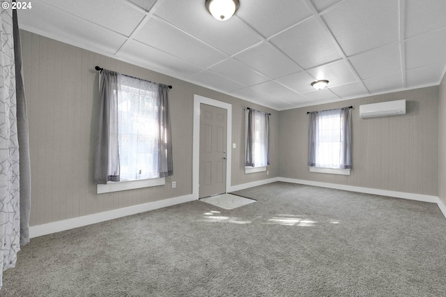 carpeted spare room featuring a wall mounted air conditioner, a paneled ceiling, and wood walls