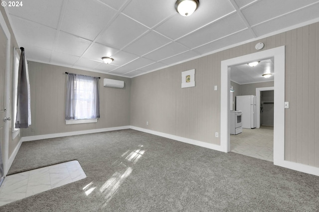 unfurnished room with carpet, a barn door, a wall mounted air conditioner, and a paneled ceiling