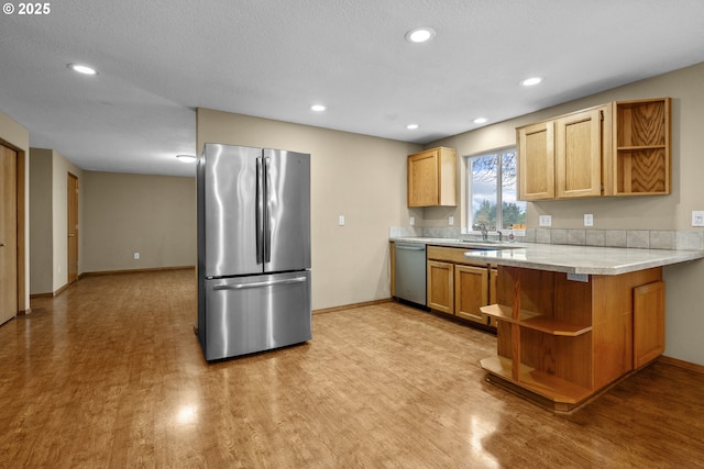 kitchen with kitchen peninsula, stainless steel appliances, light hardwood / wood-style flooring, and sink