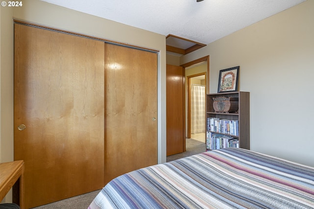 bedroom with a textured ceiling, a closet, and light carpet