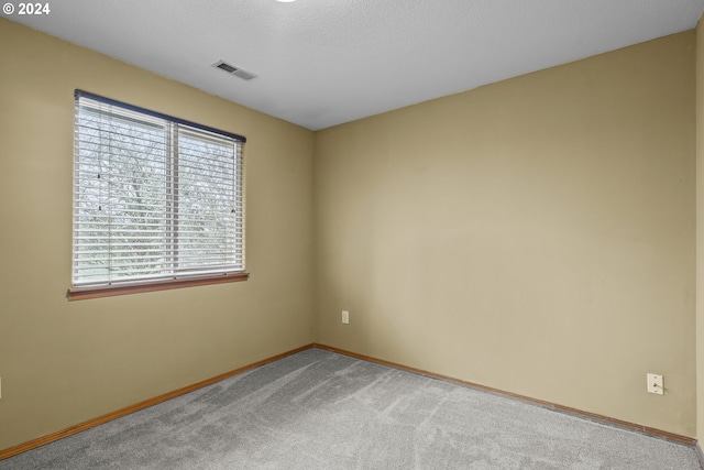 empty room with a textured ceiling and carpet floors