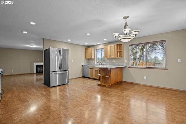 kitchen with stainless steel appliances, a chandelier, a wealth of natural light, and hanging light fixtures