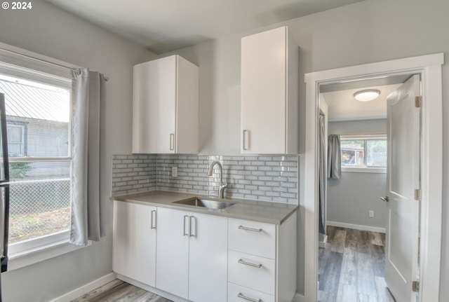 kitchen with light wood-type flooring, white cabinetry, and sink