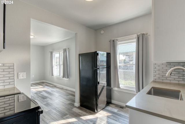 kitchen featuring backsplash, a wealth of natural light, sink, and black refrigerator