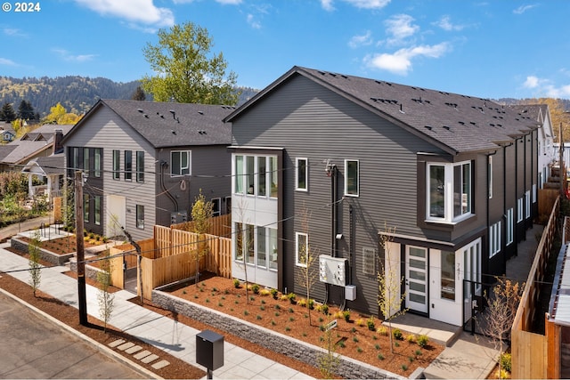 view of front of property with roof with shingles, a vegetable garden, and fence