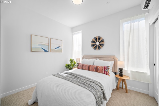 bedroom with a wall mounted air conditioner and light colored carpet